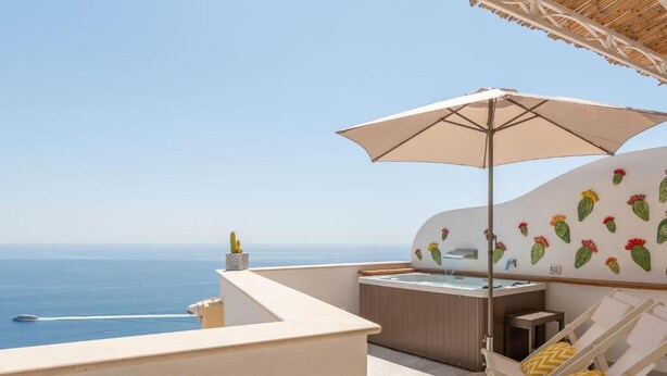 A balcony with a hot tub, lounge chairs, and a view of the sea. - Villa Marea, Praiano (Praiano)