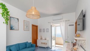 A modern living room with a blue sofa, a white cabinet, and a hanging wicker lamp. - Villa Marea, Praiano (Praiano)