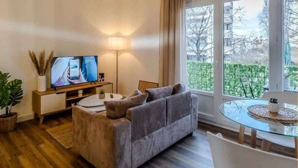 Ein modernes Wohnzimmer mit einer Couch, einem Fernseher, einer Lampe und einem Glastisch.
