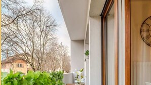 Ein Balkon mit Holztisch und Bank, einem Blumentopf und Blick auf eine Wohngegend.