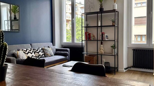 En moderne stue med en grå sofa, et træsofabord og en sort reol.
