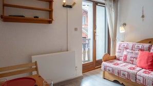 Ein gemütliches Zimmer mit einem Holztisch, einem roten Teller und einem gemusterten Sofa.