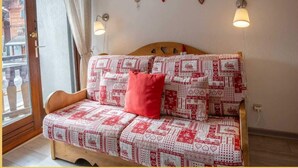 Ein gemütliches Zimmer mit einem hölzernen Bett, gemusterten Textilien und Blick durch ein großes Fenster.