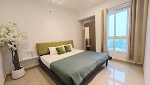 A modern bedroom with a bed, a nightstand, a potted plant, and a window with curtains.