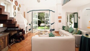 A spacious living area with a white sofa, a coffee table, and a staircase with wooden railings.