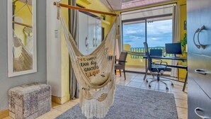 A room with a hammock chair, a desk with a computer, and a view of the outdoors. - Casa Elevación | Ocean-View Rooftop Retreat | Pool | Fiber WiFi (Playas Del Coco)