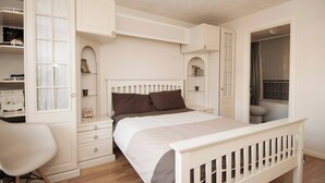 A bedroom with a bed, a chair, a wardrobe, and a bathroom visible through an open door. - Room-private Double Room Ensuite in Ches (Waltham Cross)