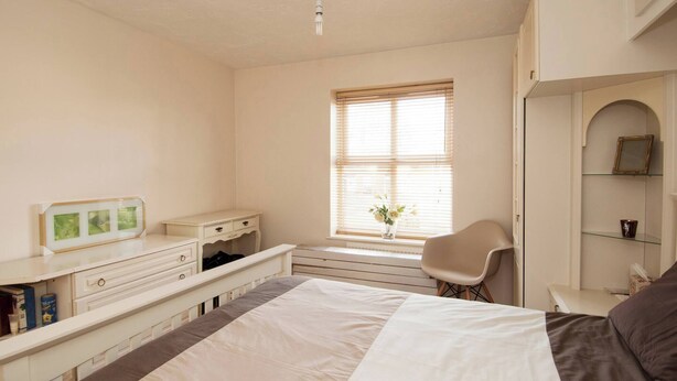 A bedroom with a bed, a desk, a chair, a window with blinds, and a shelf with a picture frame. - Room-private Double Room Ensuite in Ches (Waltham Cross)