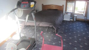 A room with a bed, a treadmill, and a small desk. - Village house with 2 bedrooms, garden and outdoor swimming pool (Distré)