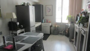A compact kitchen with a dining table, chairs, a refrigerator, and a microwave. - Village house with 2 bedrooms, garden and outdoor swimming pool (Distré)