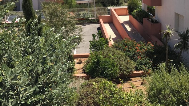 Zona residencial con edificios modernos, un cielo azul despejado y montañas al fondo.
