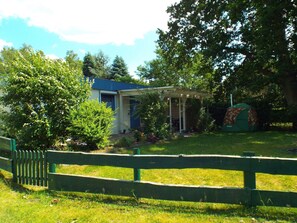 A house with a blue roof, a covered porch, and a green tent in the yard. - Bungalow in Schlowe Am See (Borkow)