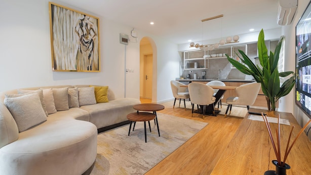 A modern living room with a sofa, coffee table, and dining area. - Aima Apartments  (Lekki)