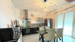 A modern kitchen with a glass dining table, black cabinets, and a stainless steel range hood. - Near Montpellier - Country house 8 to 10 persons (Saint-Clément-de-Rivière)