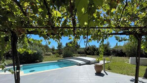 A pool area with a pergola overhead, a clear blue sky, and a well-maintained lawn. - Near Montpellier - Country house 8 to 10 persons (Saint-Clément-de-Rivière)