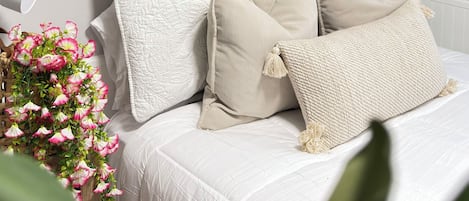 A bedroom with a bed, macrame wall hanging, and hanging plants.