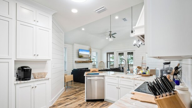 A modern kitchen with white cabinetry, a dishwasher, and a countertop with a knife block. - Unit 028 - Sea Goodness (Dauphin Island)