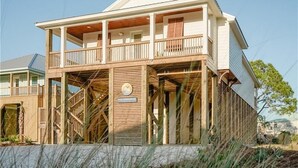 A two-story beachfront house with a balcony, wooden railings, and a sign that reads "SEA GOODNESS." - Unit 028 - Sea Goodness (Dauphin Island)