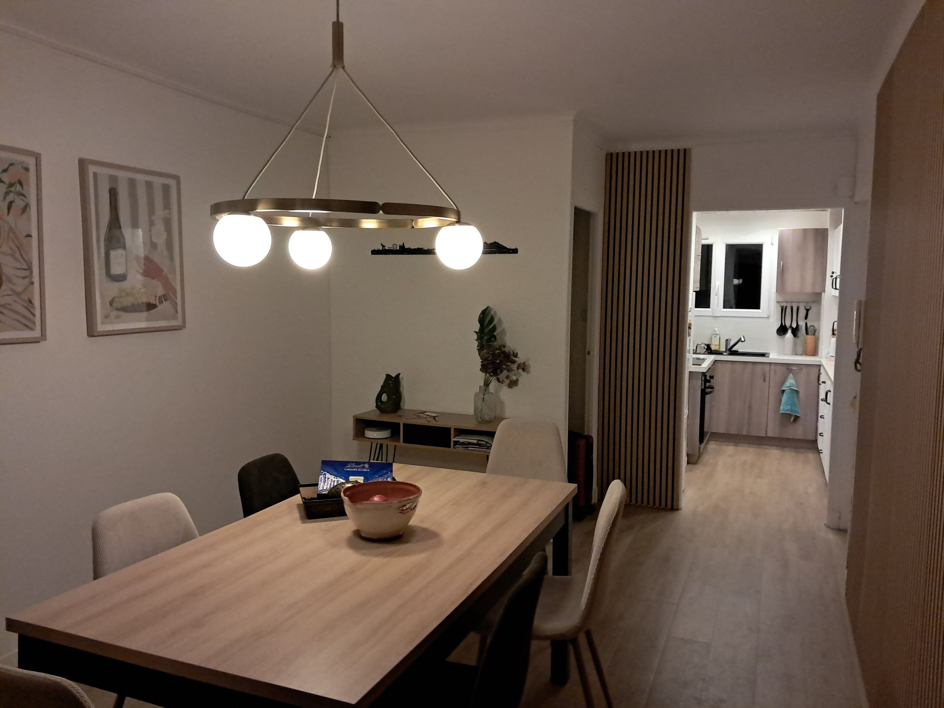 Una zona menjador moderna amb taula de fusta, cadires i llum penjant.
