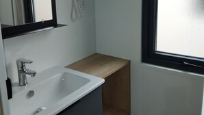 Ein Badezimmer mit Waschbecken, Spiegel, Fön und Fenster.