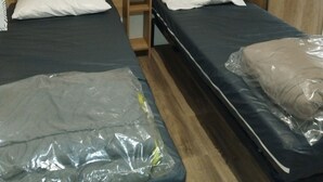 Ein Hotelzimmer mit zwei Einzelbetten, einem Holzkopfteil, einem kleinen Nachttisch und einem Kleiderschrank.