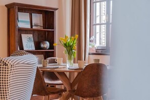 A dining area with a wooden table, chairs, and a vase of yellow flowers. - Relais Macconago (Milan)