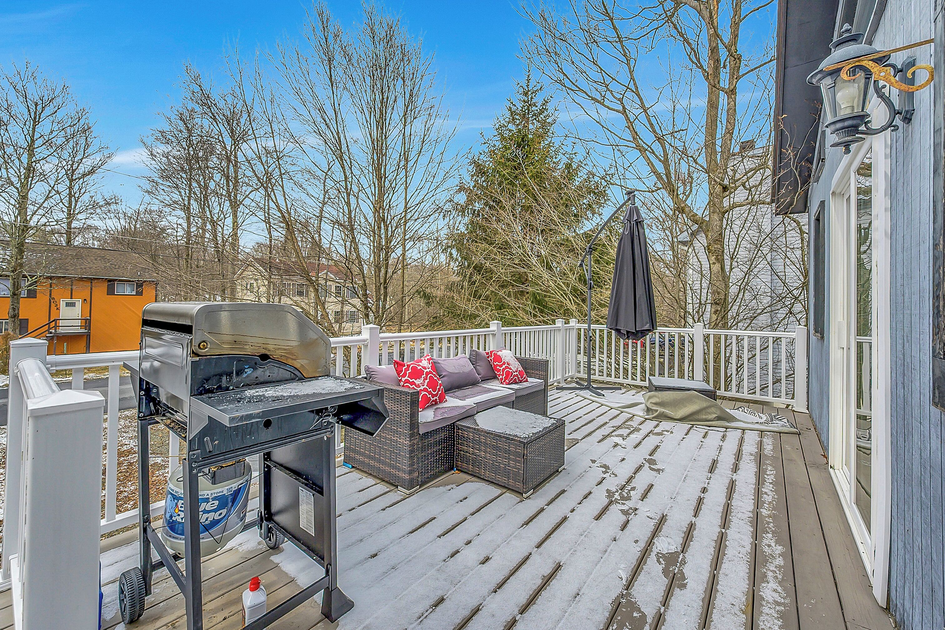 Une terrasse couverte équipée d’un barbecue, de mobilier d’extérieur et d’une rambarde blanche.