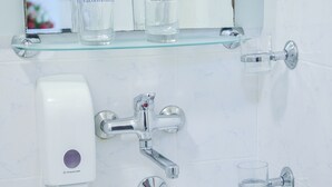 Un baño con un lavamanos blanco, un espejo y un dispensador de jabón.