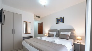Un dormitorio con cama, lámparas de noche, un armario y un cuadro en la pared.