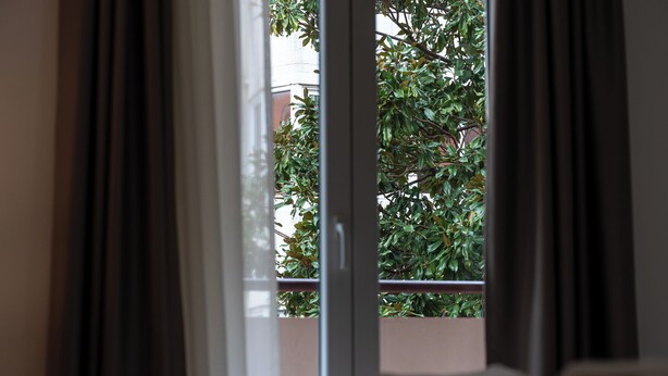Una habitación con vistas a un balcón y una ventana con cortinas.