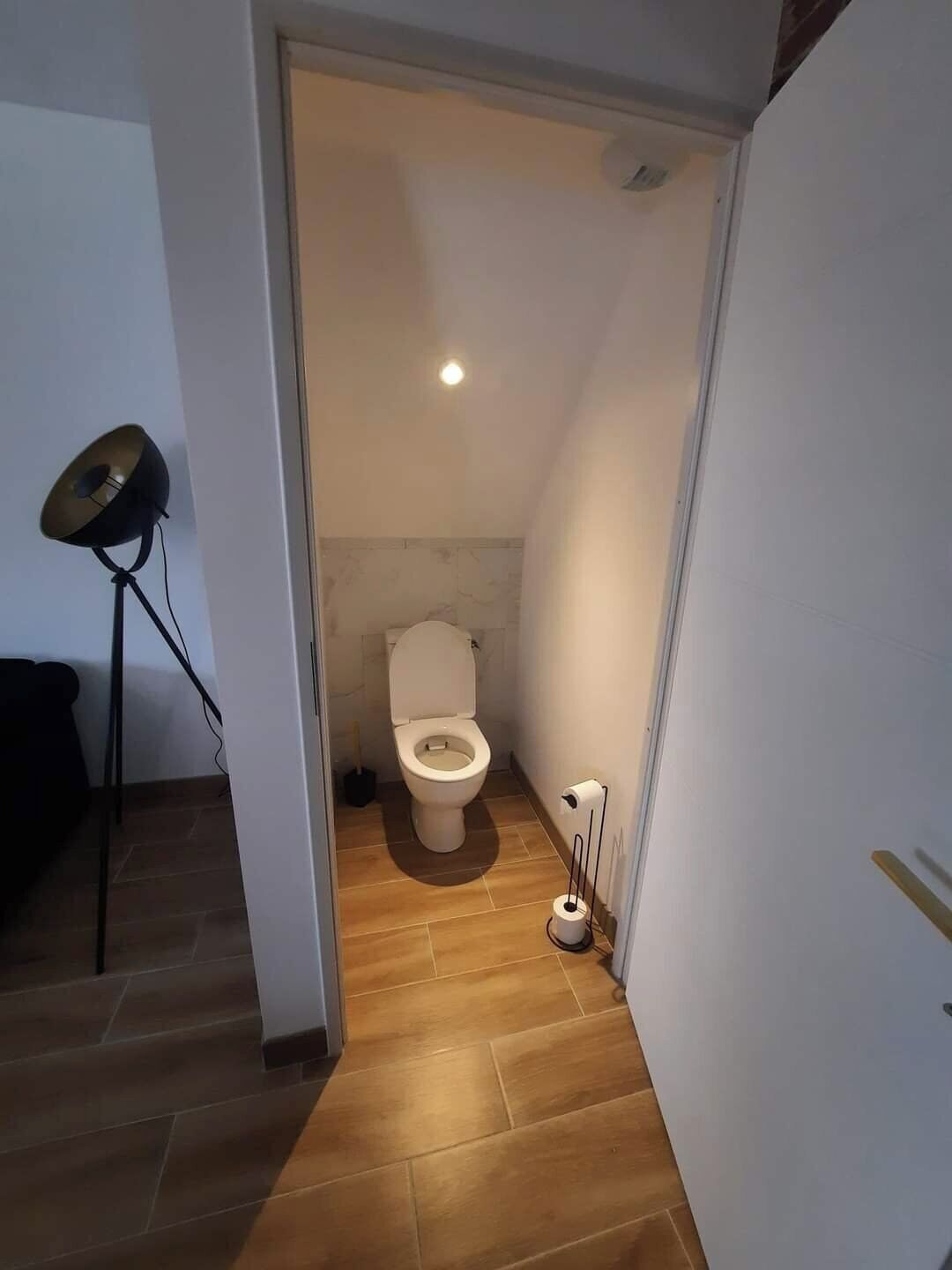Bany petit i estret amb un vàter, un bidet i una làmpada de peu.
