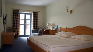 Une chambre d’hôtel avec un grand lit, un bureau, une chaise et une fenêtre avec des rideaux.