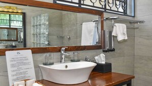 Un baño con lavamanos blanco, un espejo y un cartel sobre el ahorro de agua y energía.