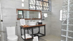 Un baño con inodoro, lavamanos, espejo y perchero para toallas.