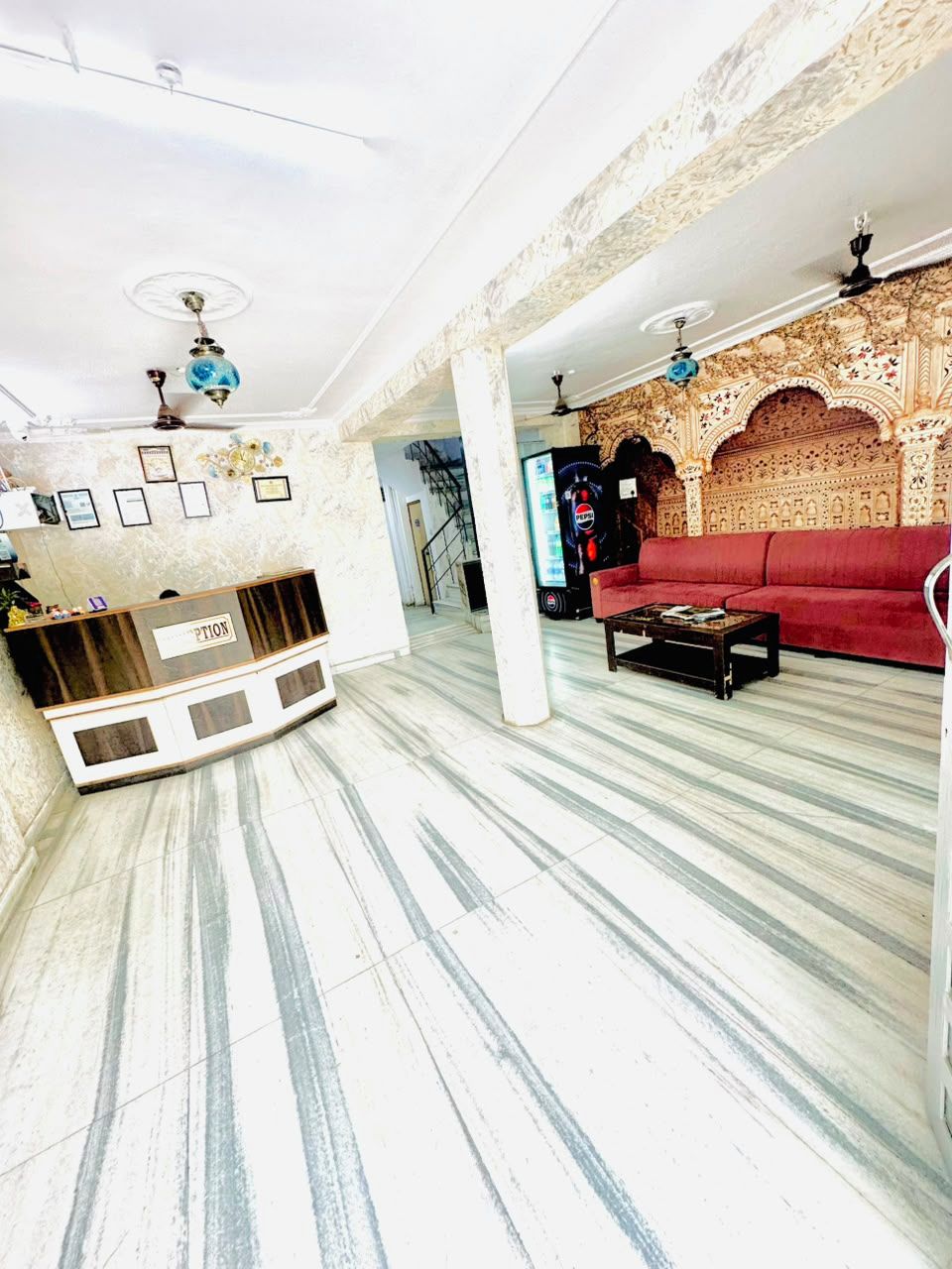 Un'ampia hall con una reception, un divano rosso e un muro decorato.