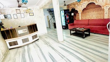 Un'ampia hall con una reception, un divano rosso e un muro decorato.