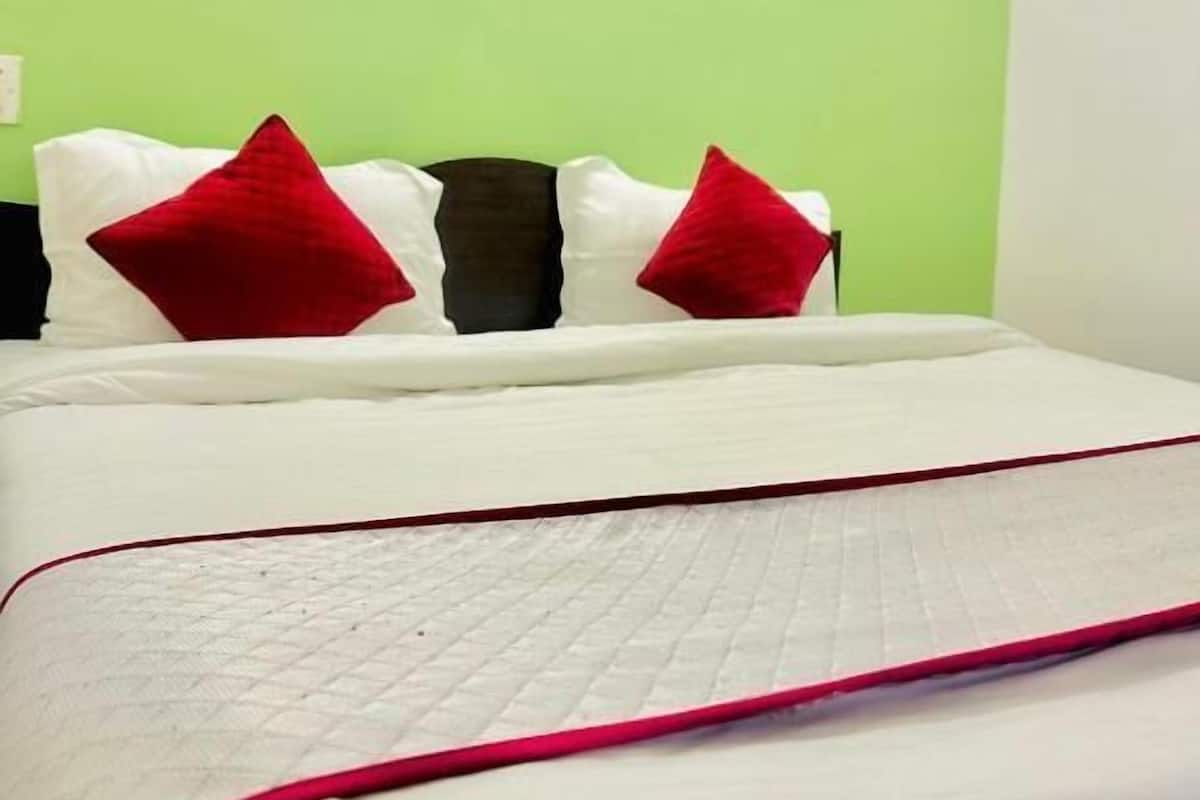 Ein Bett mit weißer Bettwäsche und roten Kissen, eine grüne Wand und ein roter Abschlussleiste am Bettrand.
