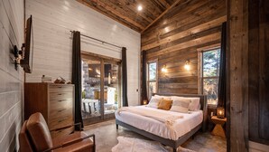 A bedroom with a wooden ceiling, a large bed with pillows, a wooden dresser, and a chair. - 4BR Broken Bow Cabin Sleeps 12 | Hot Tub, Arcade, Firepit (Broken Bow)