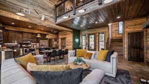 A spacious living area with a high ceiling, wooden beams, and a cozy seating arrangement. - 4BR Broken Bow Cabin Sleeps 12 | Hot Tub, Arcade, Firepit (Broken Bow)