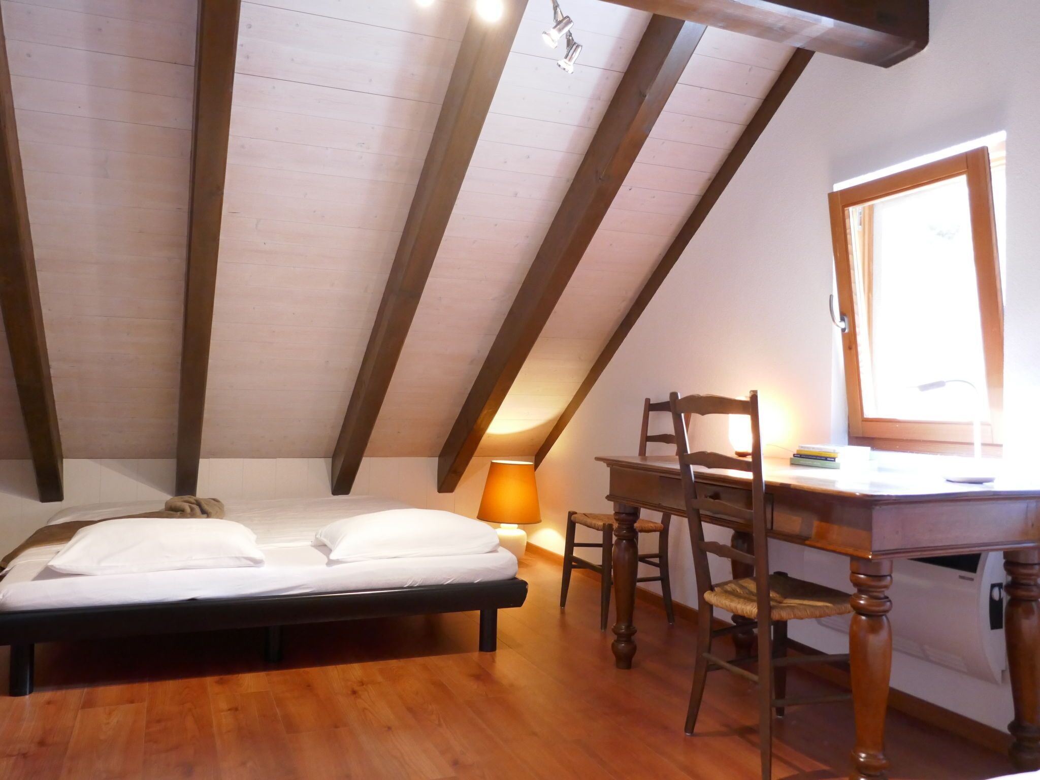 A bedroom with a bed, a desk, and a chair.