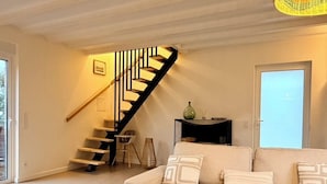 Ein Wohnzimmer mit Treppe, Sofa, Couchtisch und einer Tür.