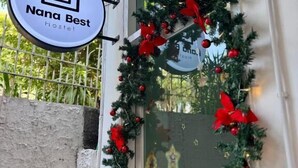 A hostel sign with a house icon and the name 'Nana Best Hostel' on a circular sign. - Nana Best Hostel (Bangkok)