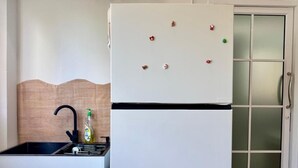 A kitchen with a white refrigerator, a black faucet, and a wooden backsplash. - Nana Best Hostel (Bangkok)