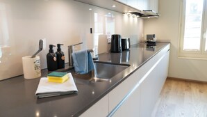 A modern kitchen with a stainless steel sink, a coffee maker, and a towel hanging on the faucet.