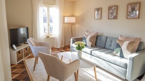 A living room with a sofa, two armchairs, a coffee table, a TV, and a lamp.