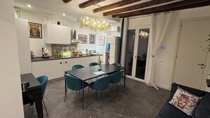 Une cuisine moderne avec des meubles blancs, une table à manger entourée de chaises turquoise et un lustre.