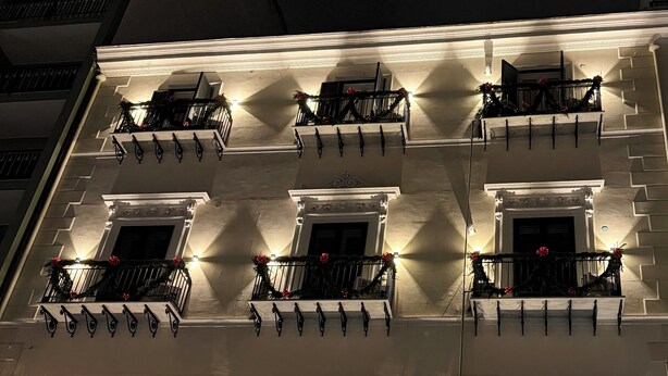 Un immeuble à plusieurs étages dont les balcons sont décorés d’ornements festifs.