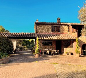 A stone building with a tiled roof, outdoor seating area, and a covered walkway.