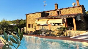 Una villa de piedra con piscina, antena parabólica y chimenea.