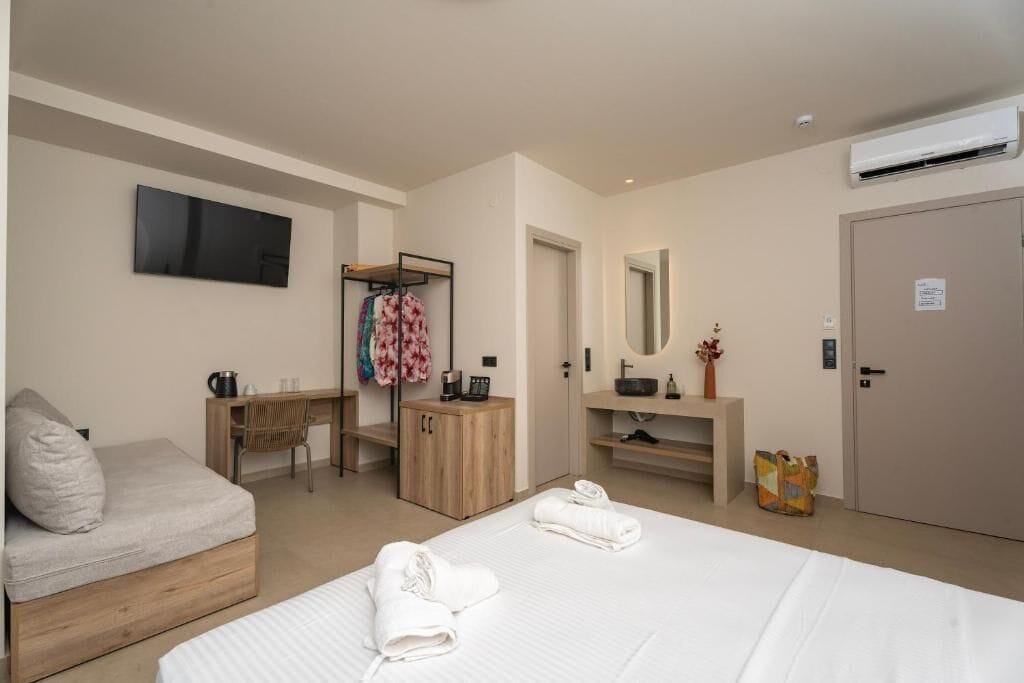 Une chambre d’hôtel moderne équipée d’un lit, d’un bureau, d’une chaise, d’une armoire, d’un miroir et d’un appareil de climatisation.